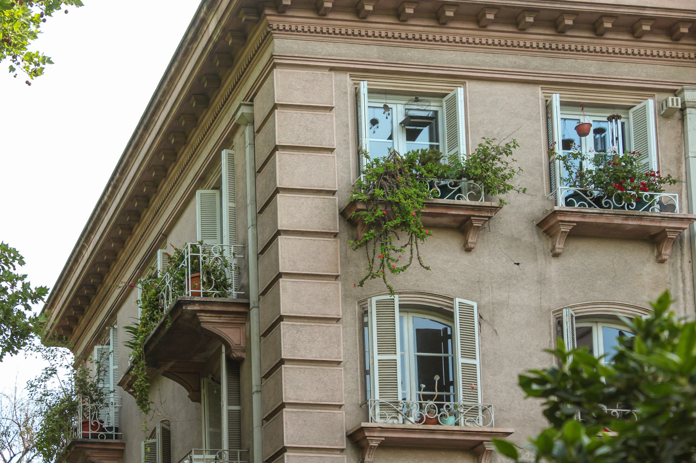 Fasáda činžovního domu s květinami na balkonech